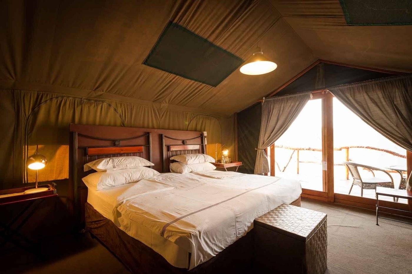 Tented bedroom with crisp white linens and wooden furniture at Camp Savuti