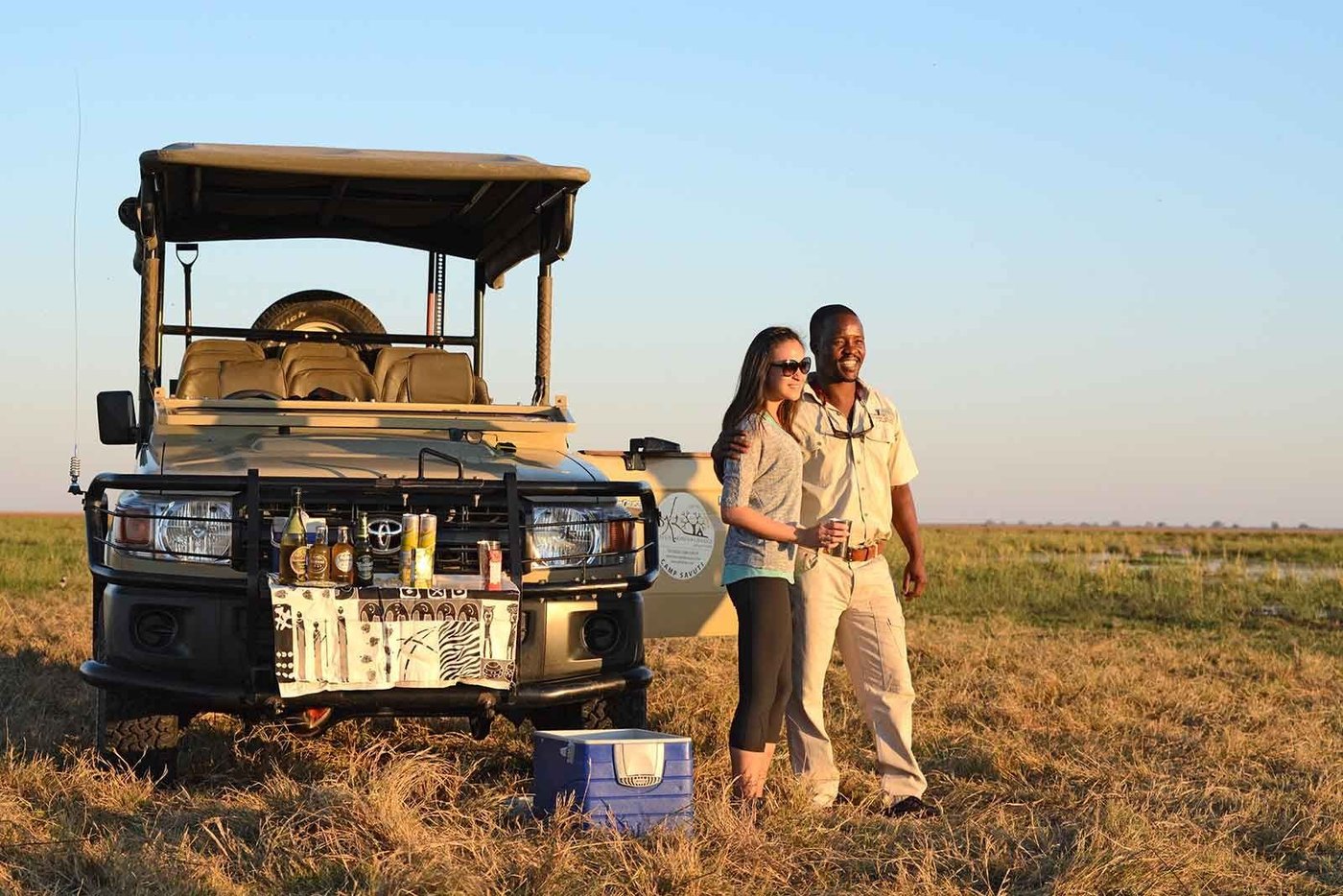 Guide and guest beside a safari vehicle on the plains near Camp Savuti