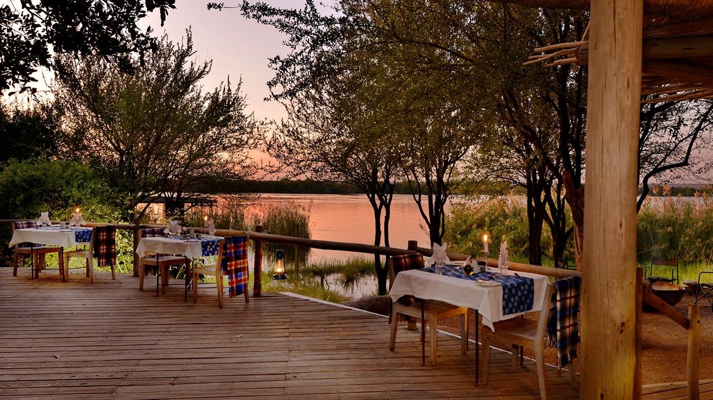 Outdoor dining deck overlooking the river at sunset at Chobe Bakwena Lodge, Chobe