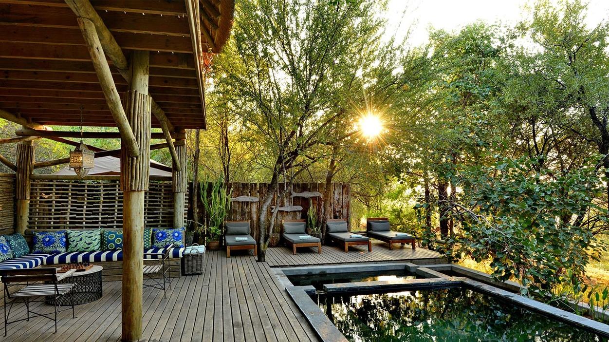 Swimming pool deck with loungers at sunset at Chobe Bakwena Lodge