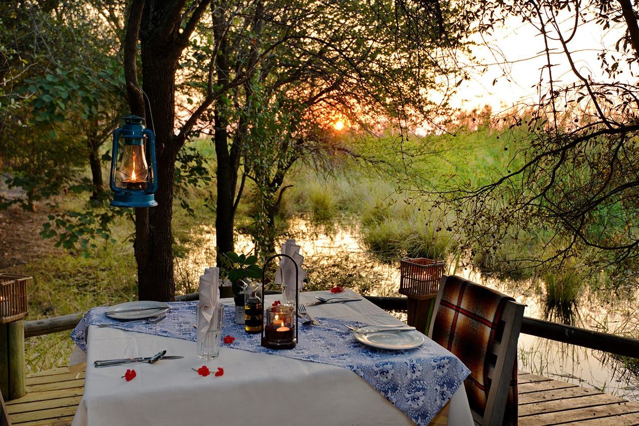 Candlelit dinner table set on the deck at dusk at Chobe Bakwena Lodge