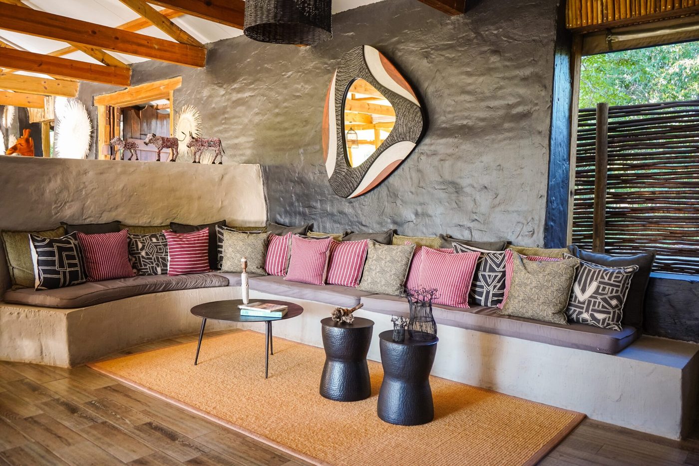Lounge seating area with cushions under a thatched roof at Chobe Elephant Camp