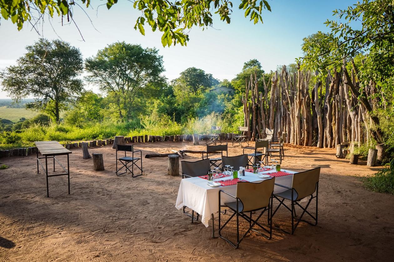 Outdoor dining table set among reed screens at dusk at Chobe Elephant Camp