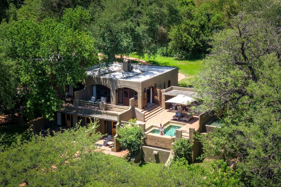 Aerial view of the lodge buildings and pool amid riverside trees at Chobe Game Lodge, Chobe