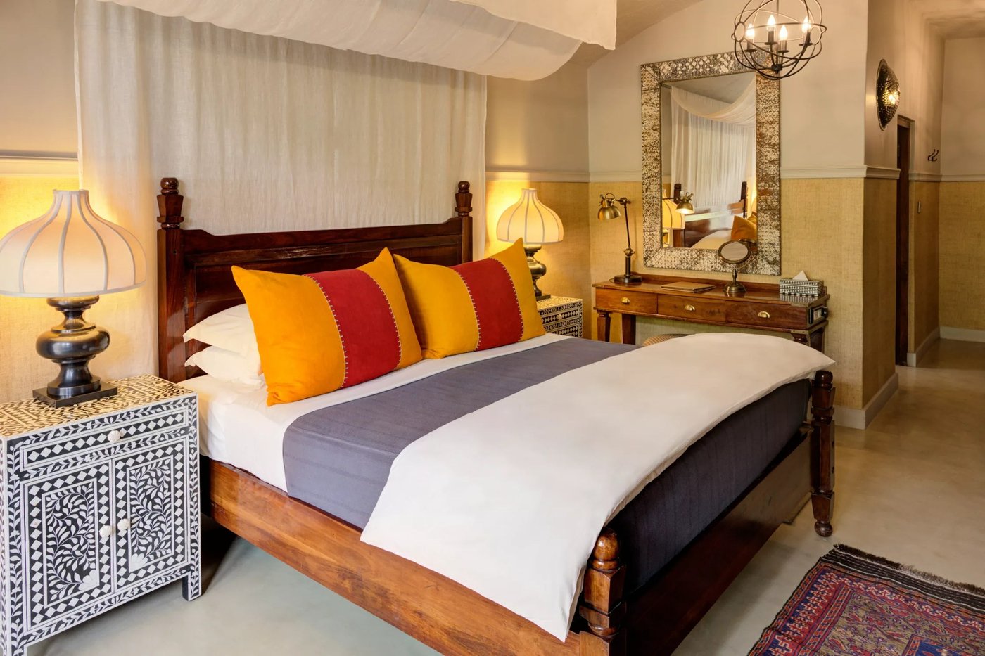 Bedroom with four-poster bed and orange accent cushions at Chobe Game Lodge