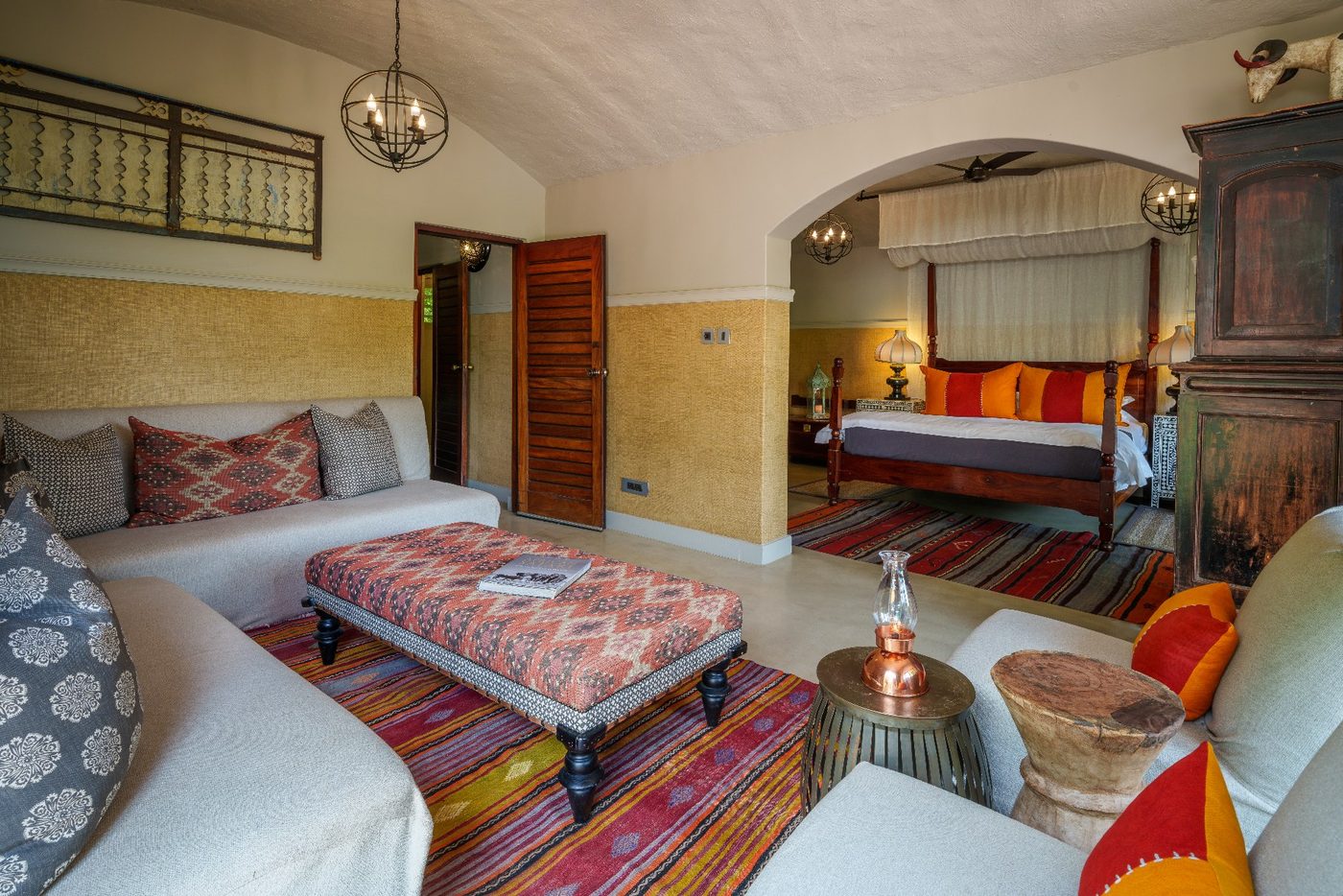 Suite lounge area beside the bed with patterned textiles at Chobe Game Lodge