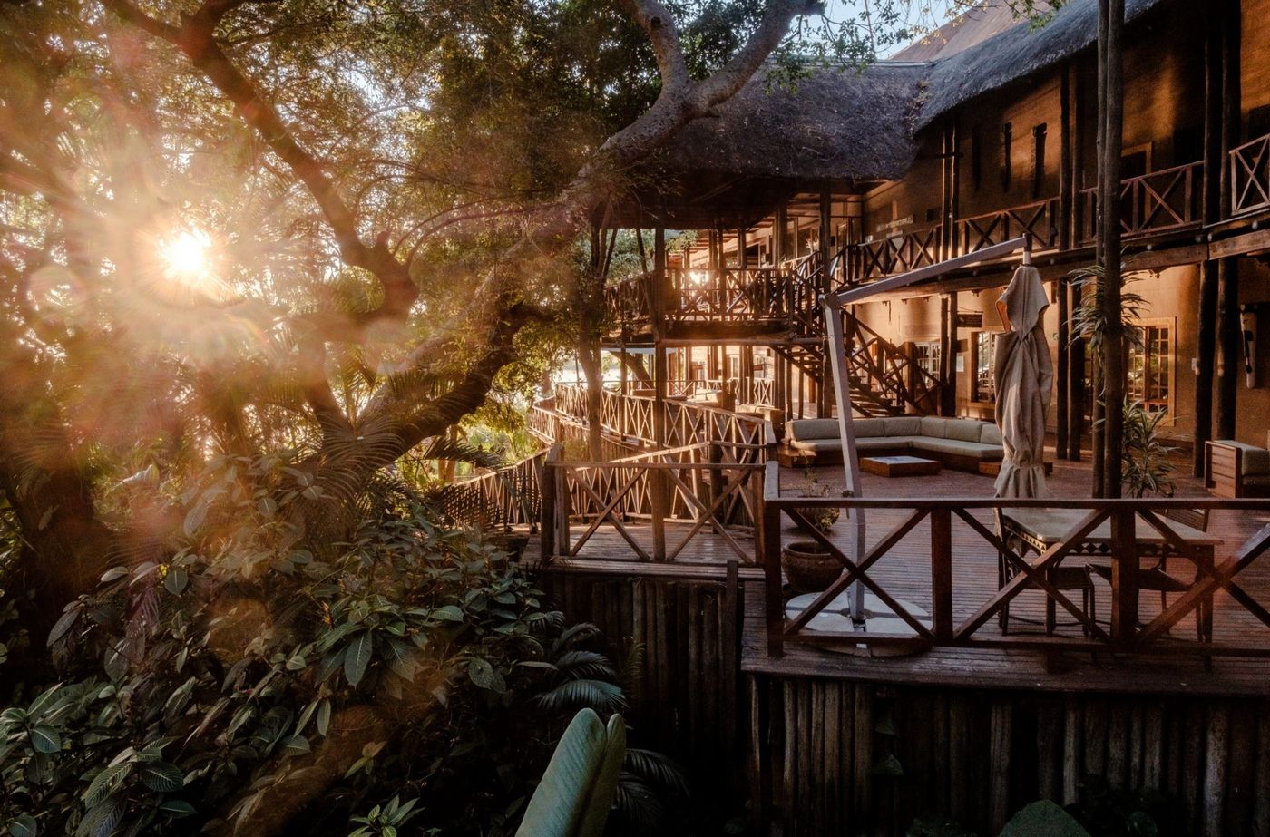 Wooden lodge deck lit at dusk above the river at Chobe Marina Lodge, Chobe