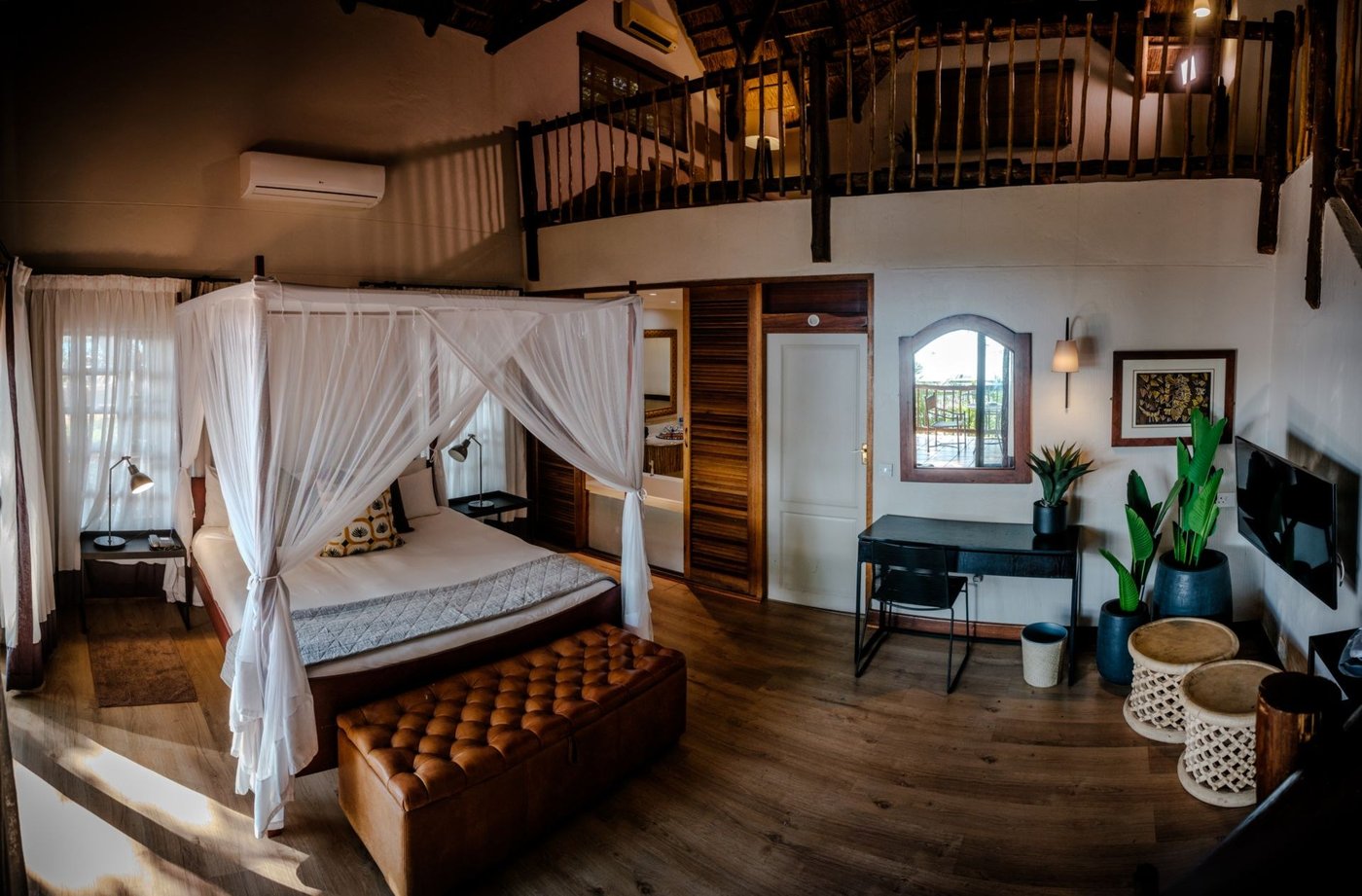 Loft suite bedroom with a sitting area below at Chobe Marina Lodge