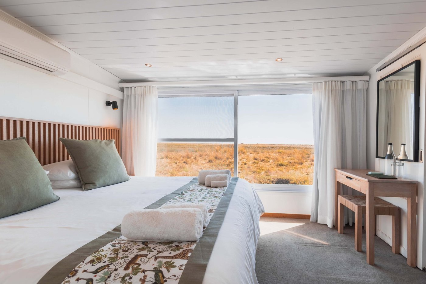 Houseboat bedroom with a river view through large windows at Chobe Princess