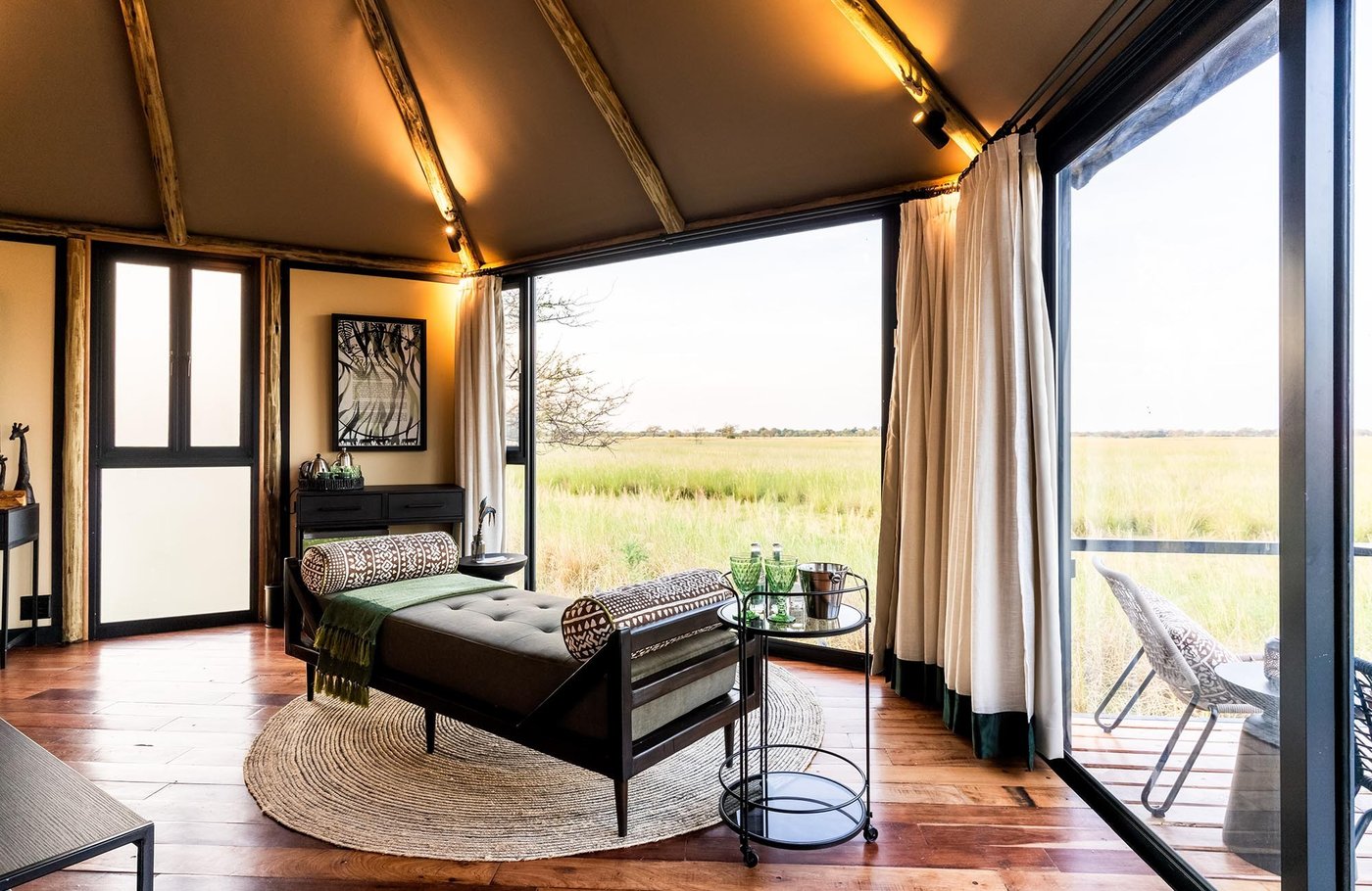 Bedroom with wooden floors and floor-to-ceiling windows at Chobe River Camp