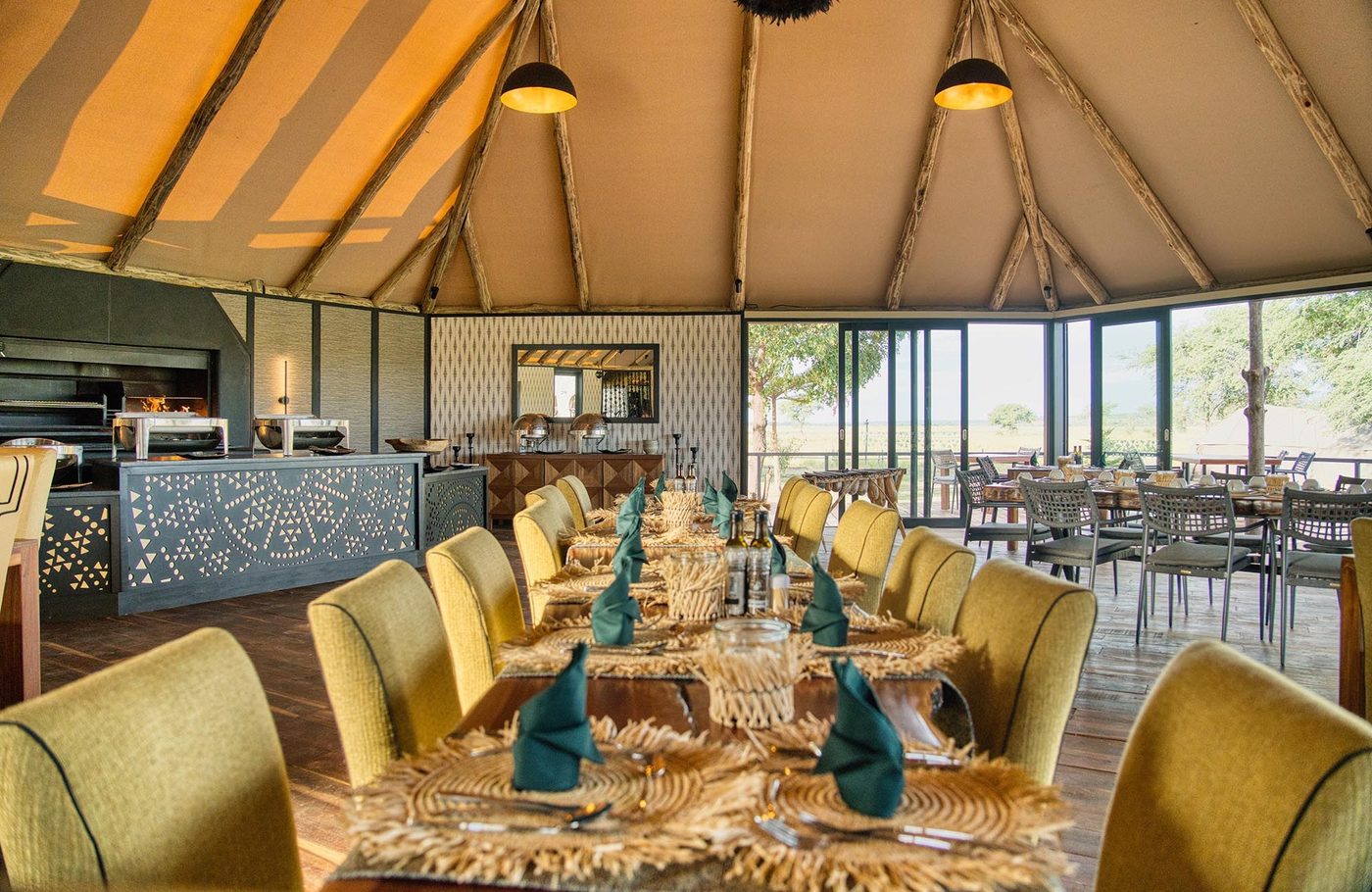 Dining room with a long table and yellow chairs at Chobe River Camp