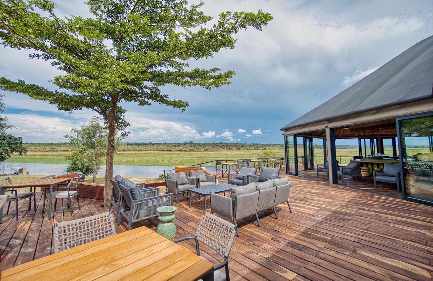 Deck lounge overlooking the floodplain under a large tree at Chobe River Camp
