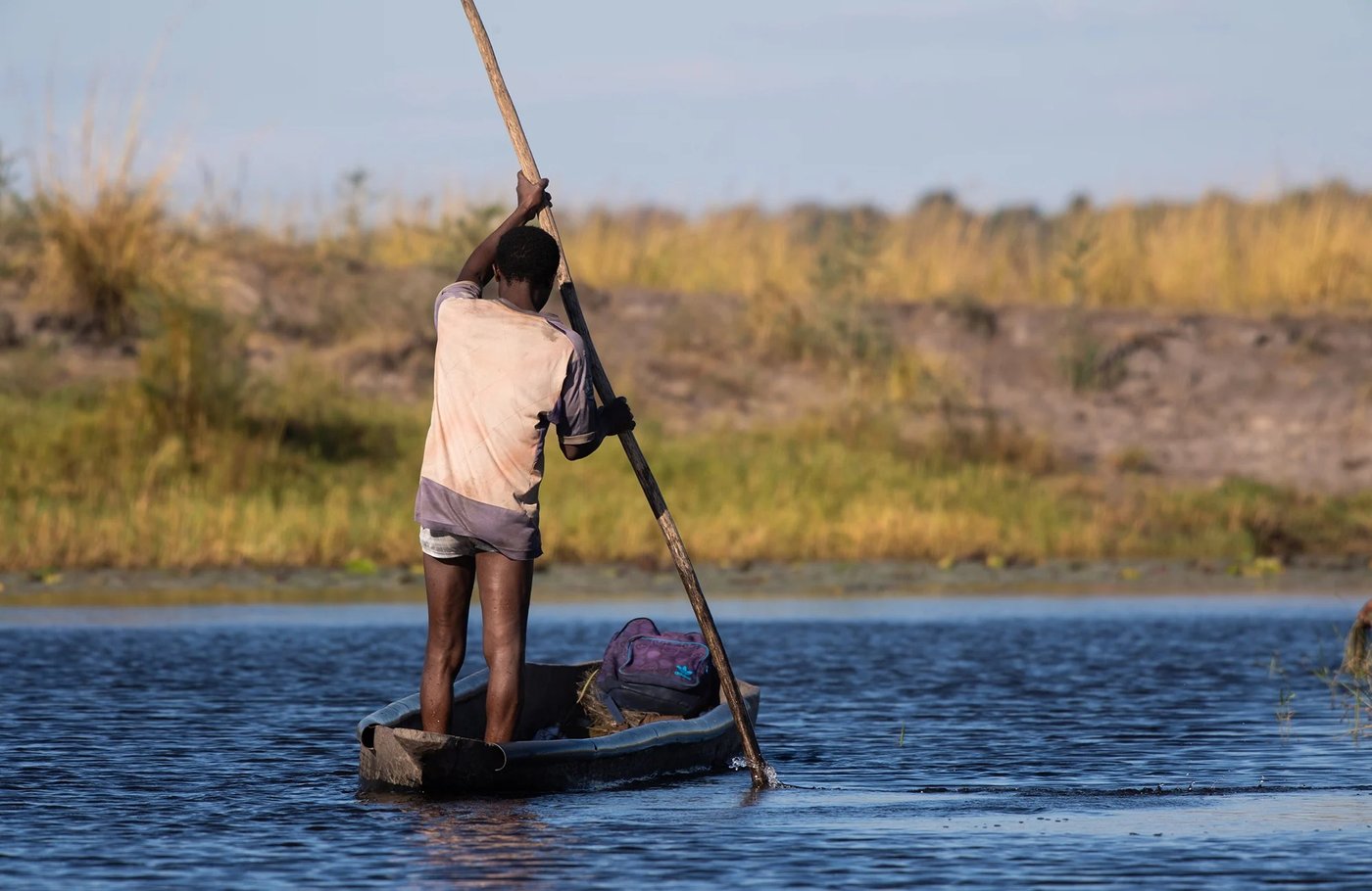 Guide poling a mokoro canoe across the water near Chobe River Camp