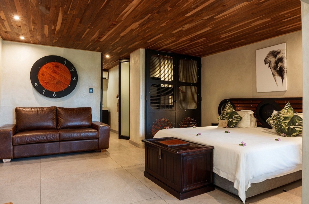 Bedroom with a leather sofa and dark wood furniture at Chobe River Lodge