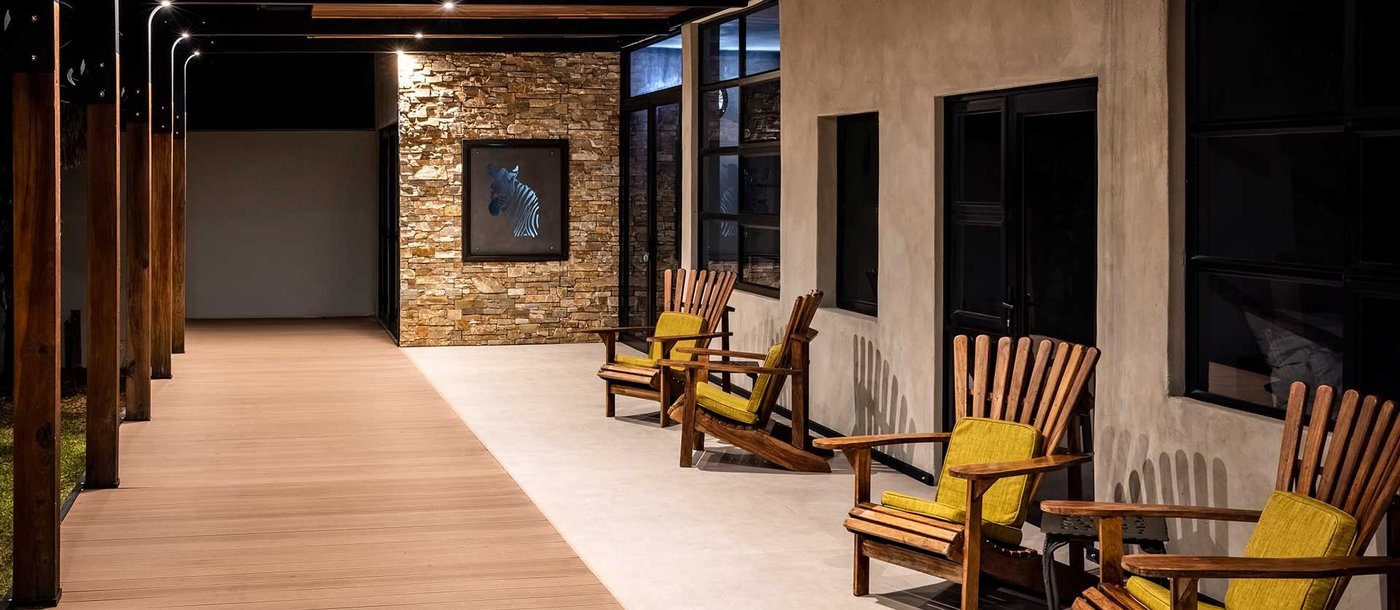 Covered walkway leading to a yellow-chaired lounge at Chobe River Lodge