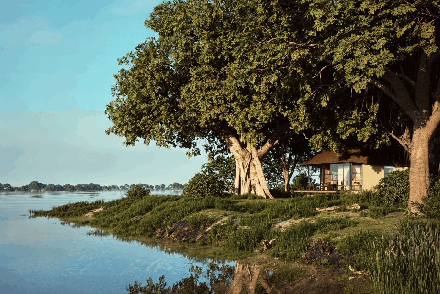 Lodge buildings reflected across the river beneath a large tree at Chobe Savanna Lodge, Chobe