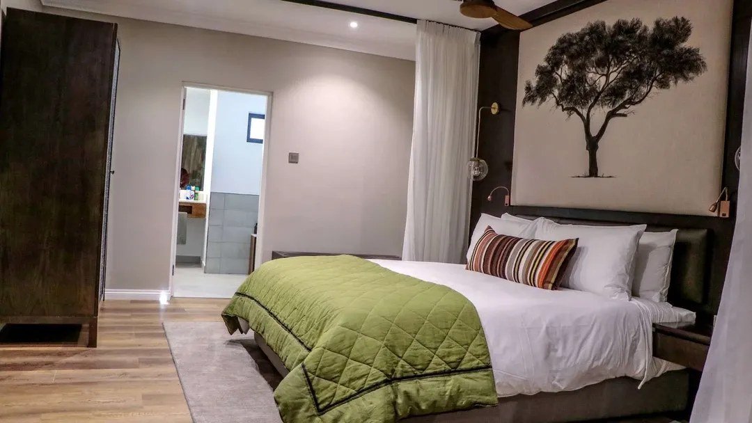 Bedroom with a tree-silhouette artwork above the headboard at Cresta Mowana Safari Resort & Spa