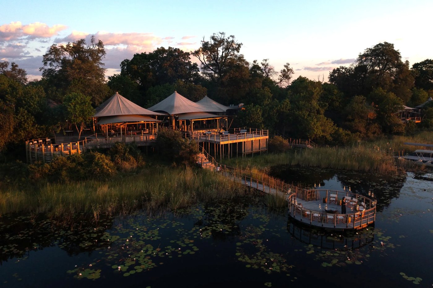 Aerial view of tented camp and boat on the floodplain at dusk at DumaTau Camp, Chobe