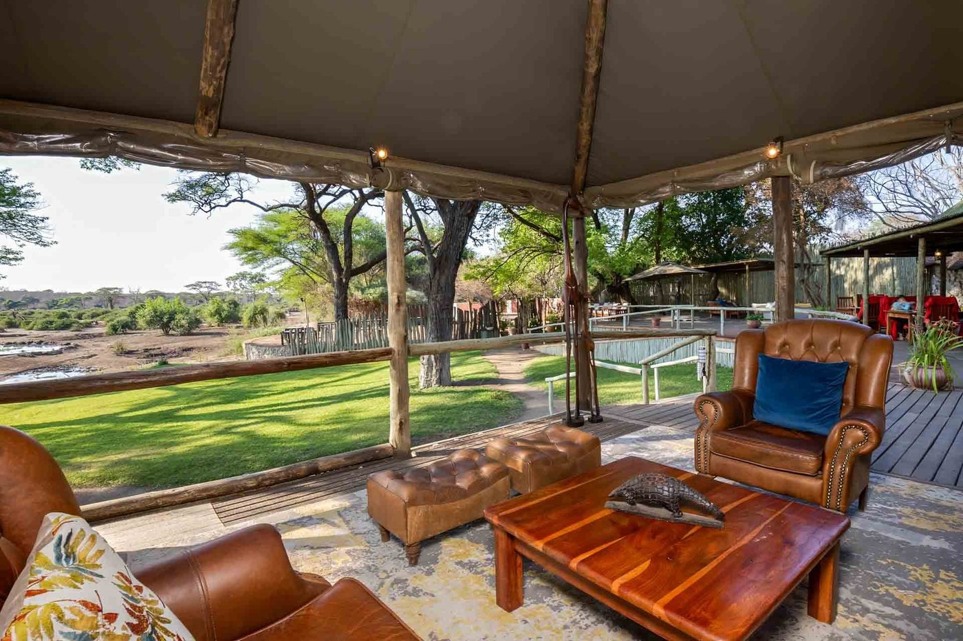 Covered lounge deck with leather chairs overlooking the lawn at Elephant Valley Lodge