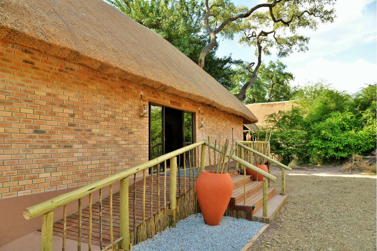 Thatched entrance building with a stone pathway at Jackalberry Chobe