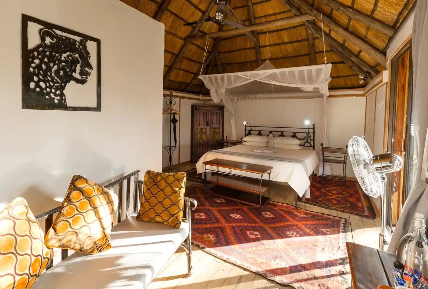 Bedroom with leopard wall art and orange cushions at Kubu Lodge