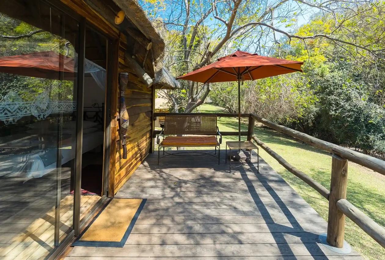 Covered patio with an umbrella table beside the garden at Kubu Lodge