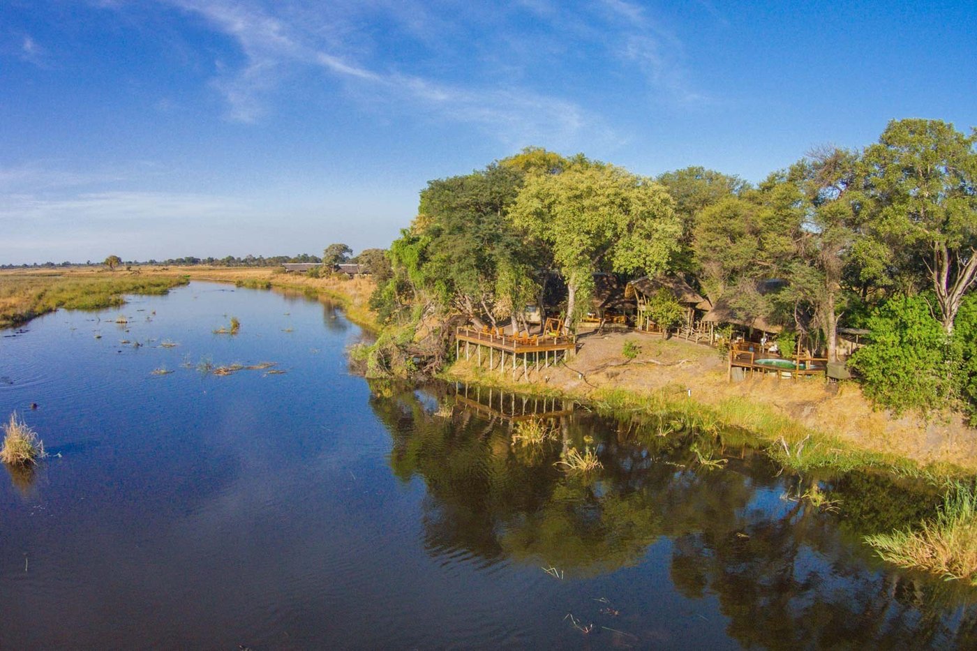 Wide view of the lagoon with the camp nestled among trees at Lagoon Camp, Chobe