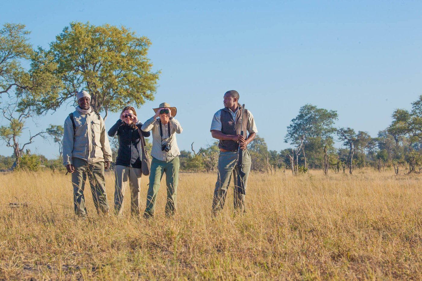 Guides and guests scanning the grassland with binoculars near Lagoon Camp