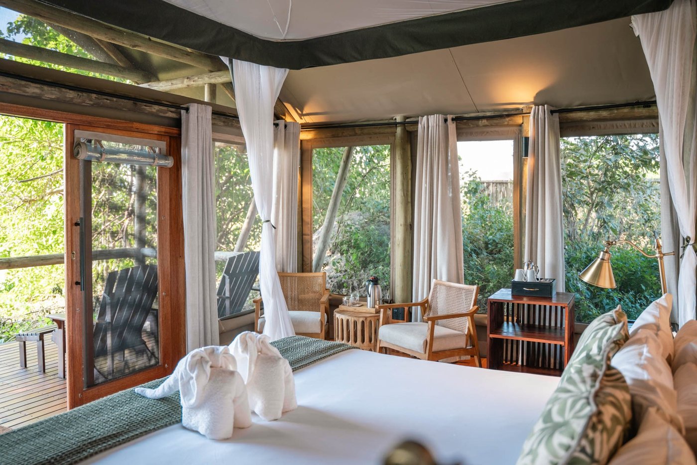 Bedroom with canopy drapes and elephant-shaped towel art at Lebala Camp