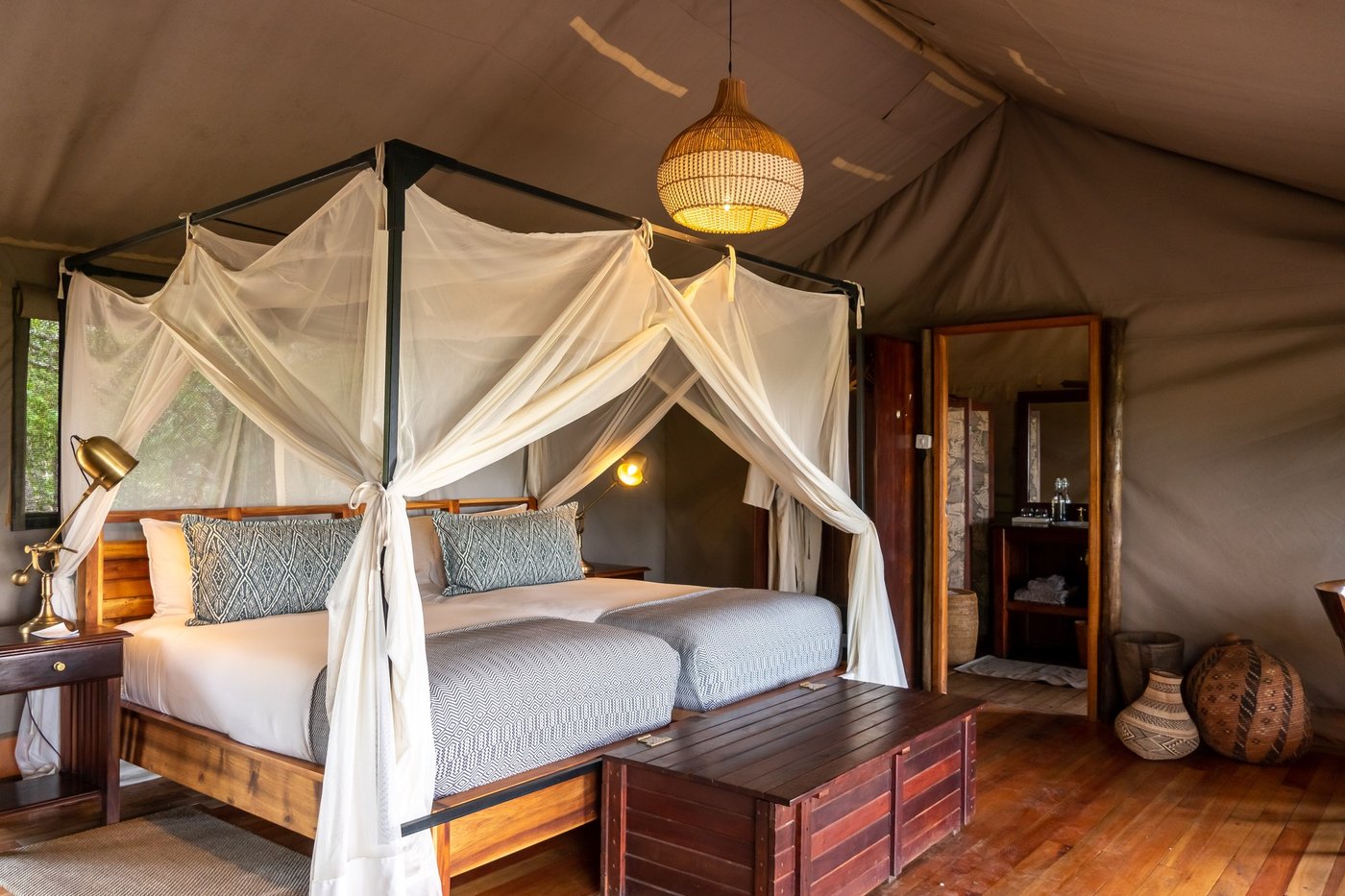 Canopy bed tent with a hanging pendant light at Linyanti Bush Camp