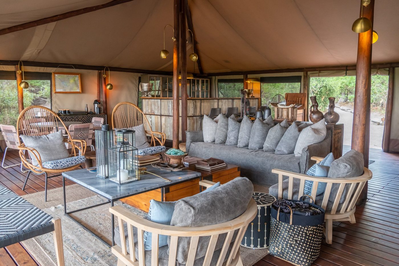 Tented lounge with hanging chairs and lanterns at Linyanti Bush Camp