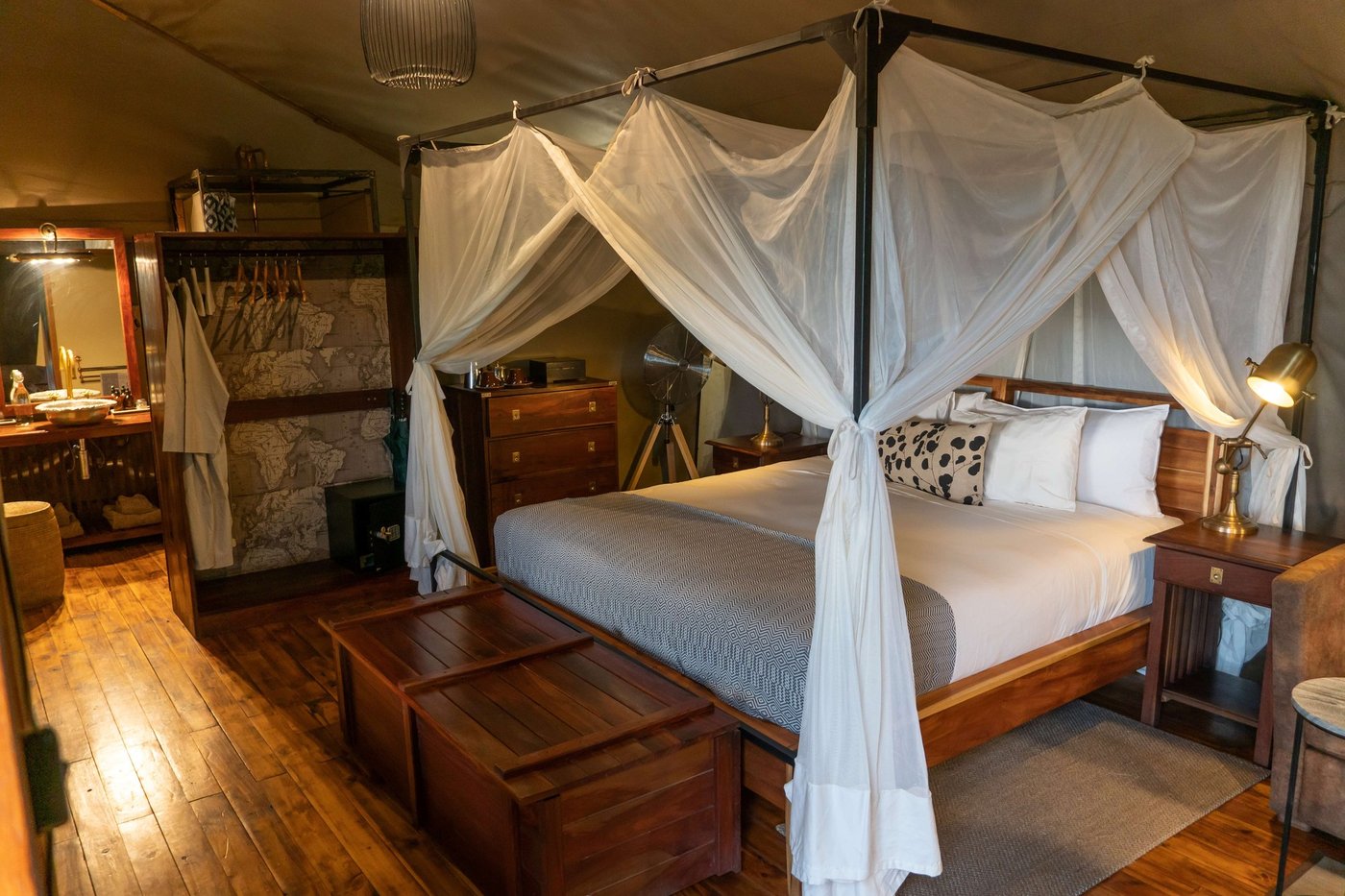 Canopy bed tent with a wooden dresser at Linyanti Ebony