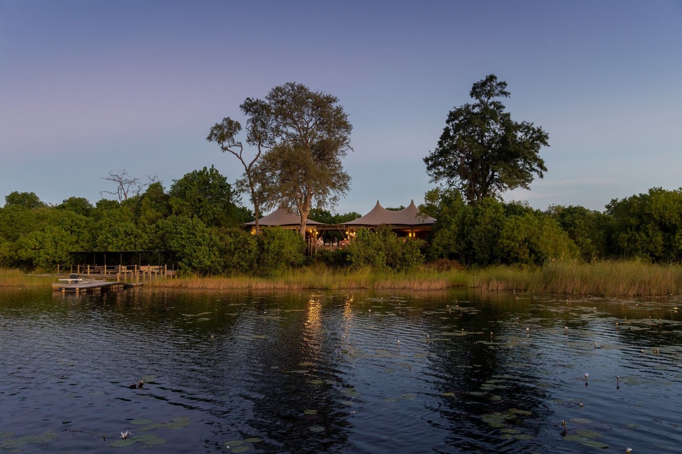 View of the camp across still water among trees at Little DumaTau