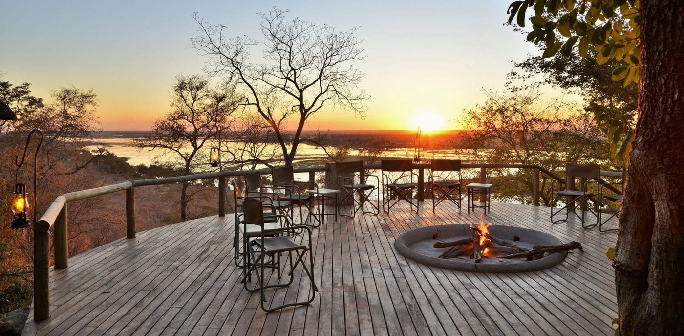 Deck lounge overlooking the floodplain under a dramatic sunset sky at Muchenje Safari Lodge, Chobe