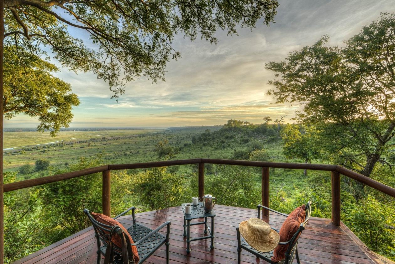 Balcony chairs overlooking the floodplain under a stormy sky at Muchenje Safari Lodge