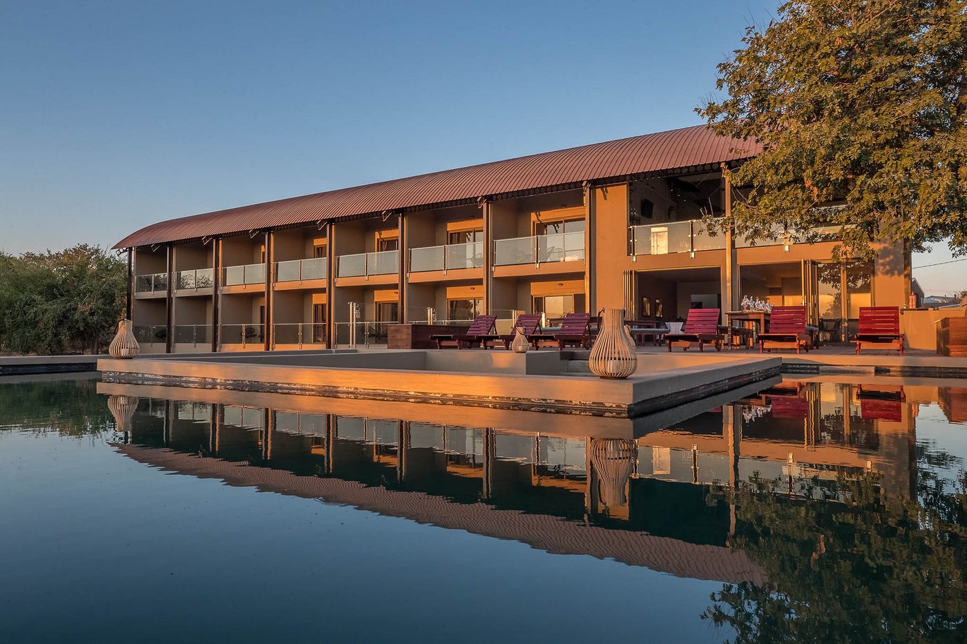 Hotel building reflected in the water at dusk at Pangolin Chobe Hotel, Chobe