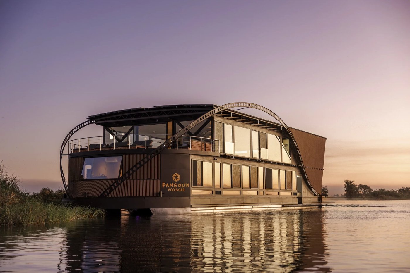 Houseboat with a rounded bow on the water at dusk at Pangolin Voyager, Chobe