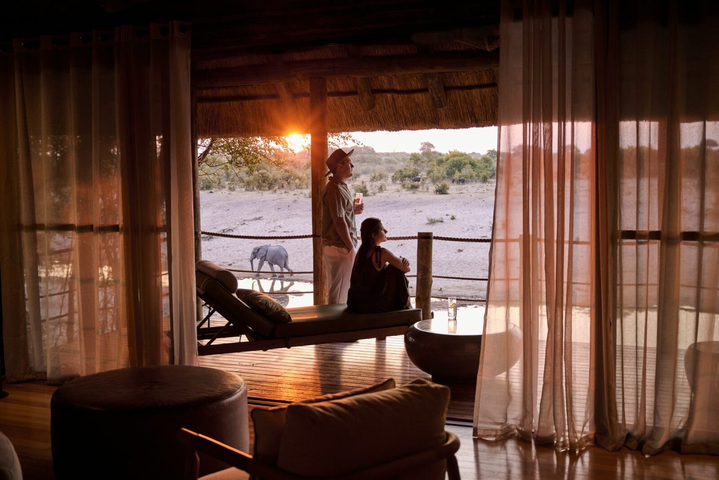 Guest on the room balcony overlooking elephants at the waterhole at Savute Safari Lodge