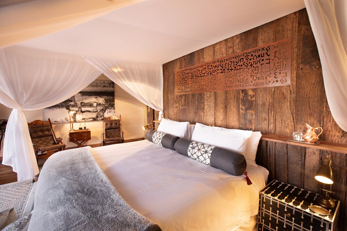 Bedroom with rustic wood paneling and canopy netting at Selinda Camp
