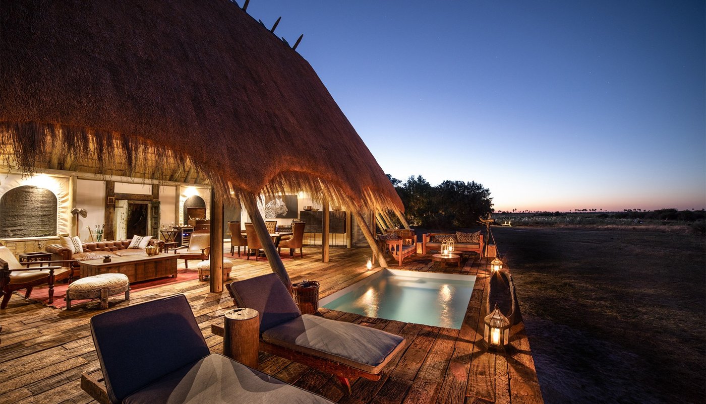 Pool deck beside the thatched main building at dusk at Selinda Camp