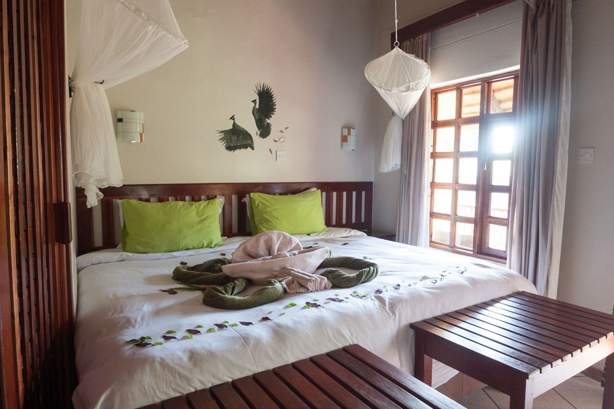 Bedroom with green cushions and bird artwork at Water Lily Lodge