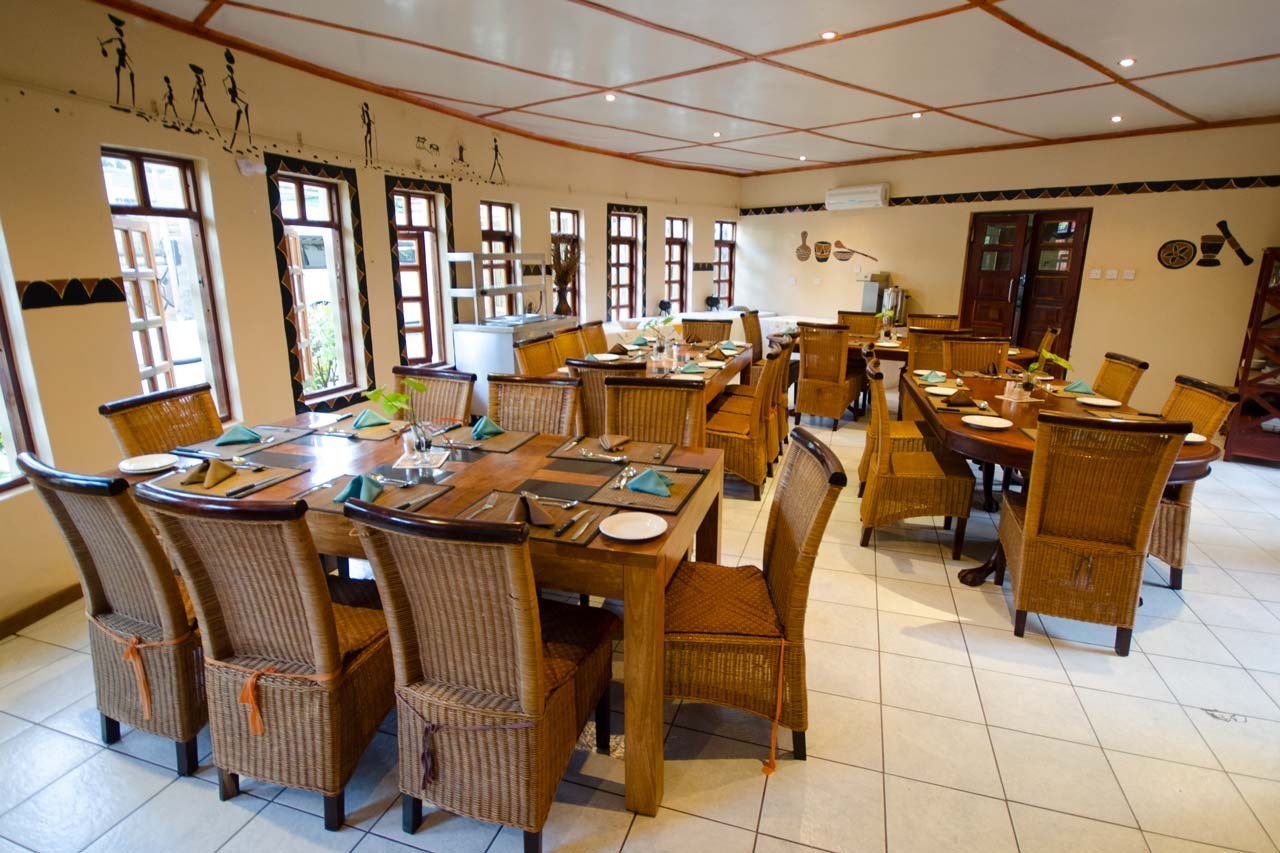 Dining room with a long table and wicker chairs at Water Lily Lodge