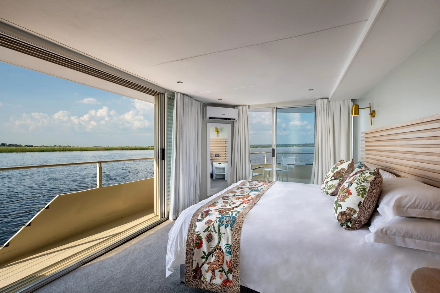 Cabin bedroom opening onto a private balcony over the river at Zambezi Queen