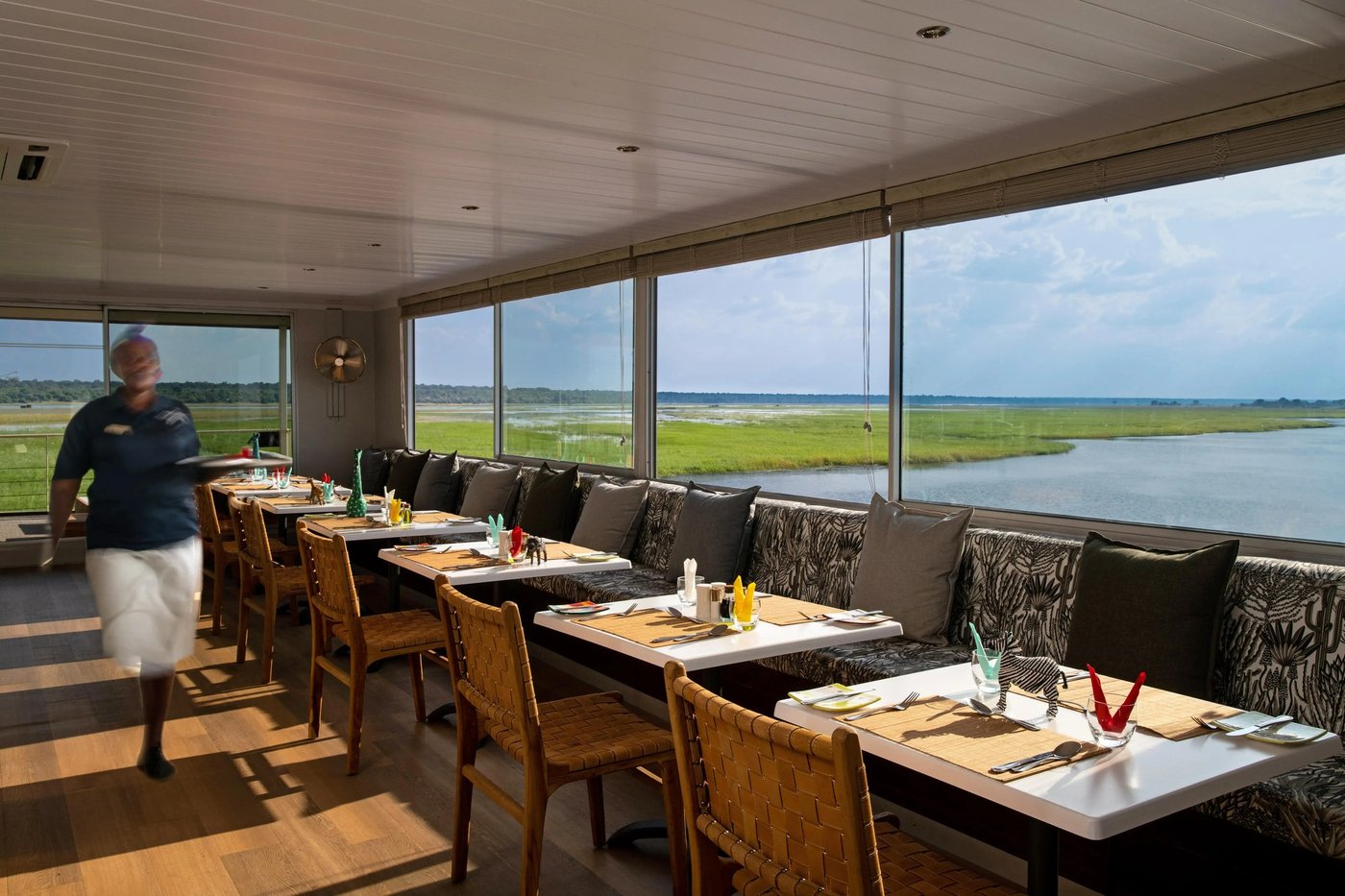 Dining area with a long table overlooking the river at Zambezi Queen