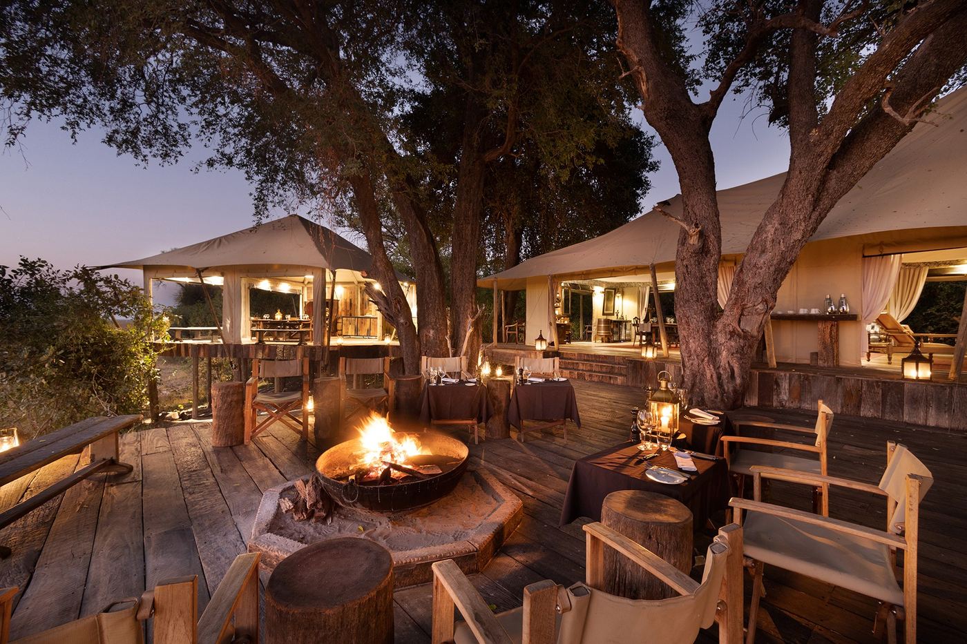 Fire pit lounge deck glowing at dusk at Zarafa Camp, Chobe