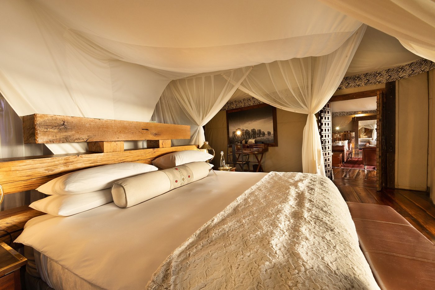 Bedroom with rustic plank walls and canopy drapes at Zarafa Camp