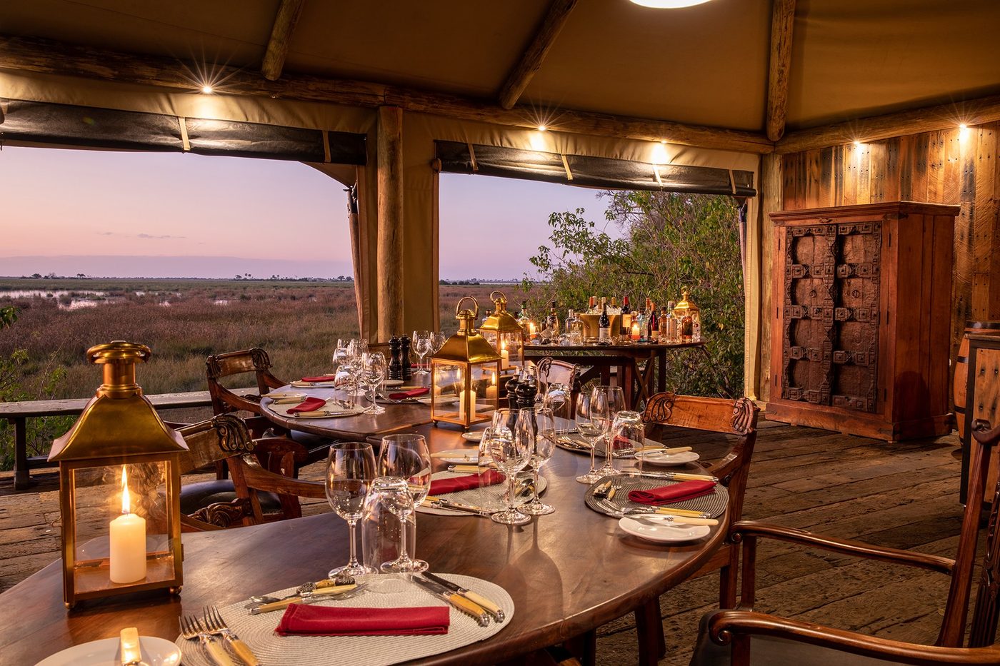 Dining room with a long table set beneath the thatched roof at Zarafa Camp